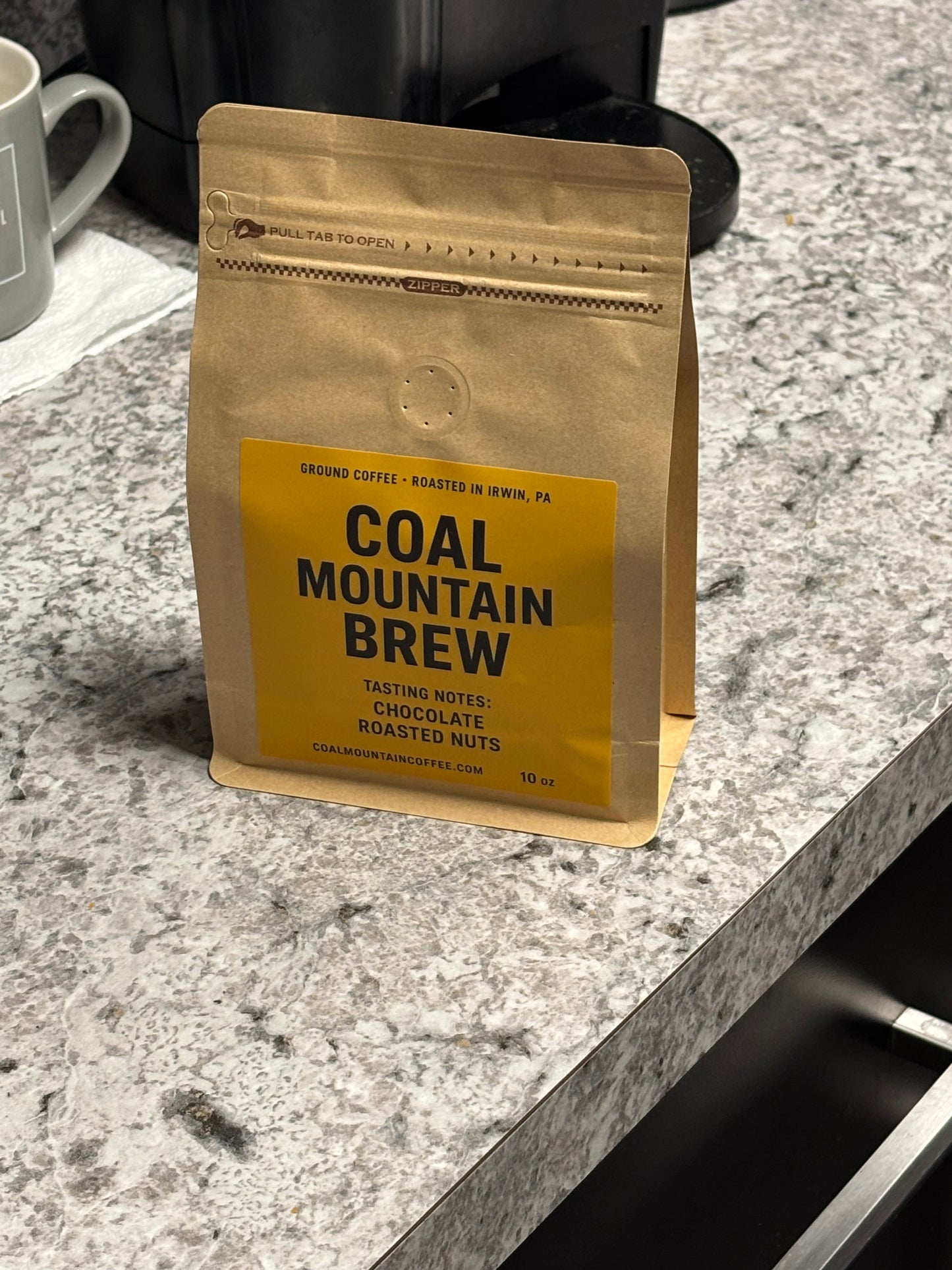 Coffee package labeled 'Coal Mountain Brew' on a marble surface